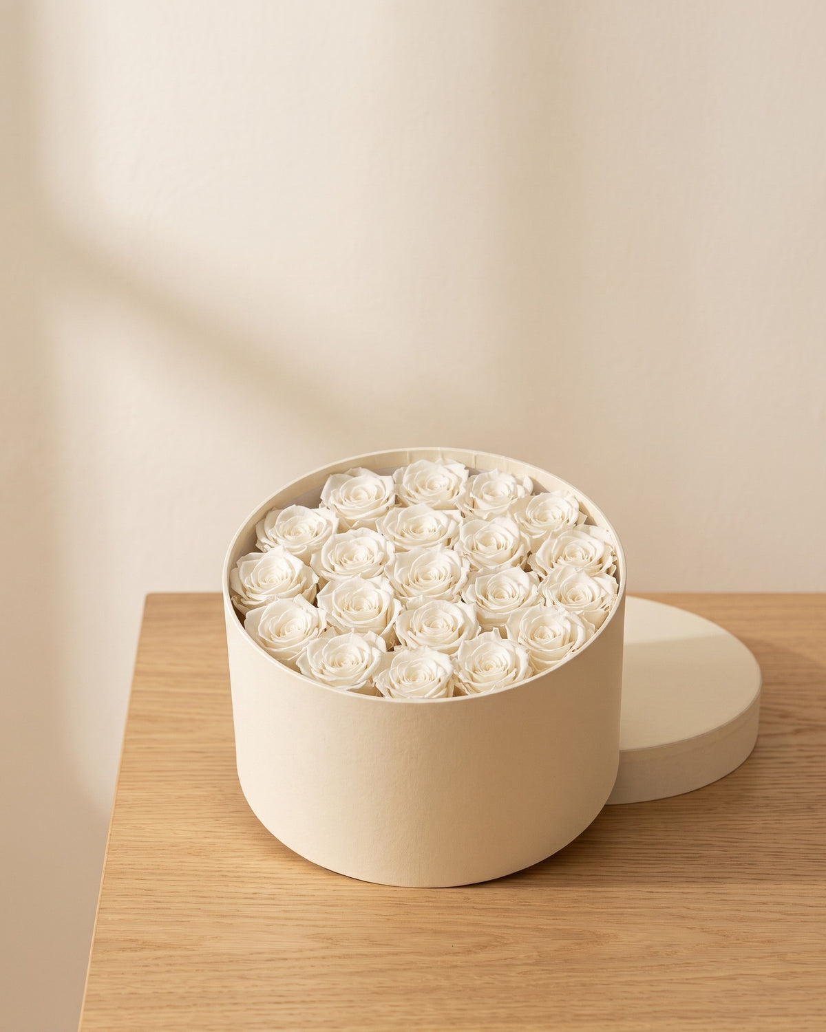 Cabezas de rosa preservada blanca en una caja redonda de regalo, ambientada. Caja de regalo no incluida.