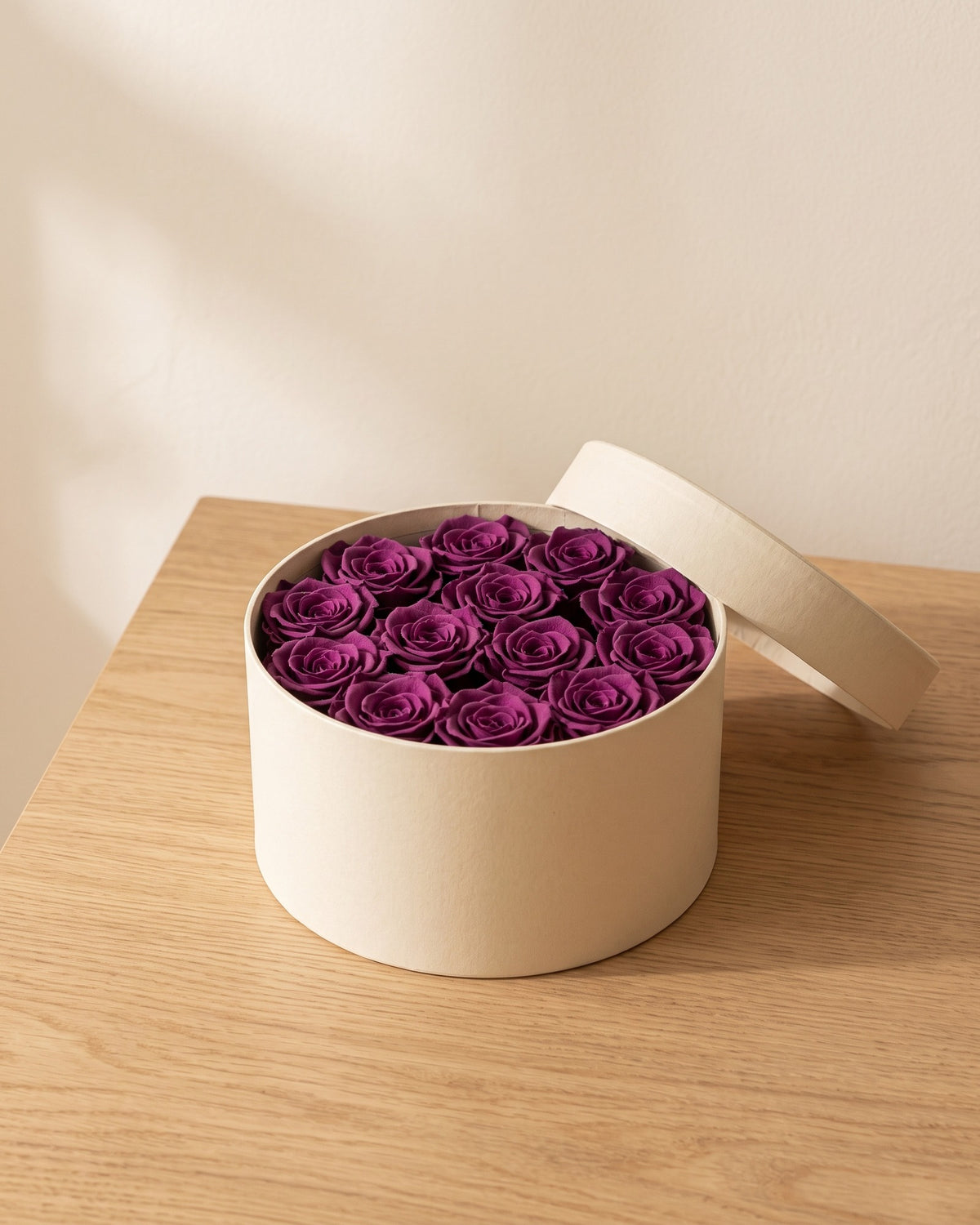 Cabezas de rosa preservada morada en una caja redonda de regalo, ambientada. Caja de regalo no incluida.