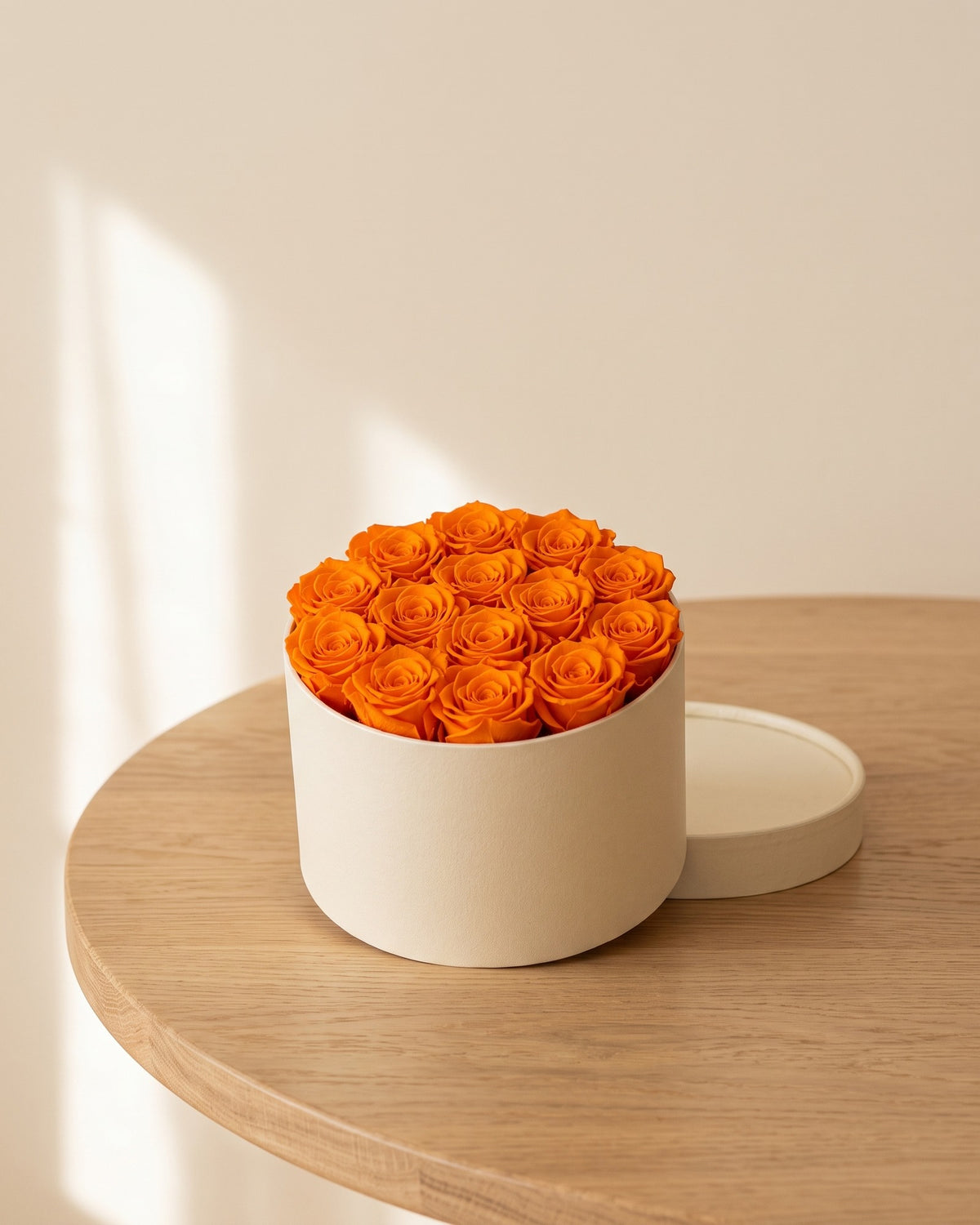 Cabezas de rosa preservada naranja en una caja redonda de regalo, ambientada. Caja de regalo no incluida.