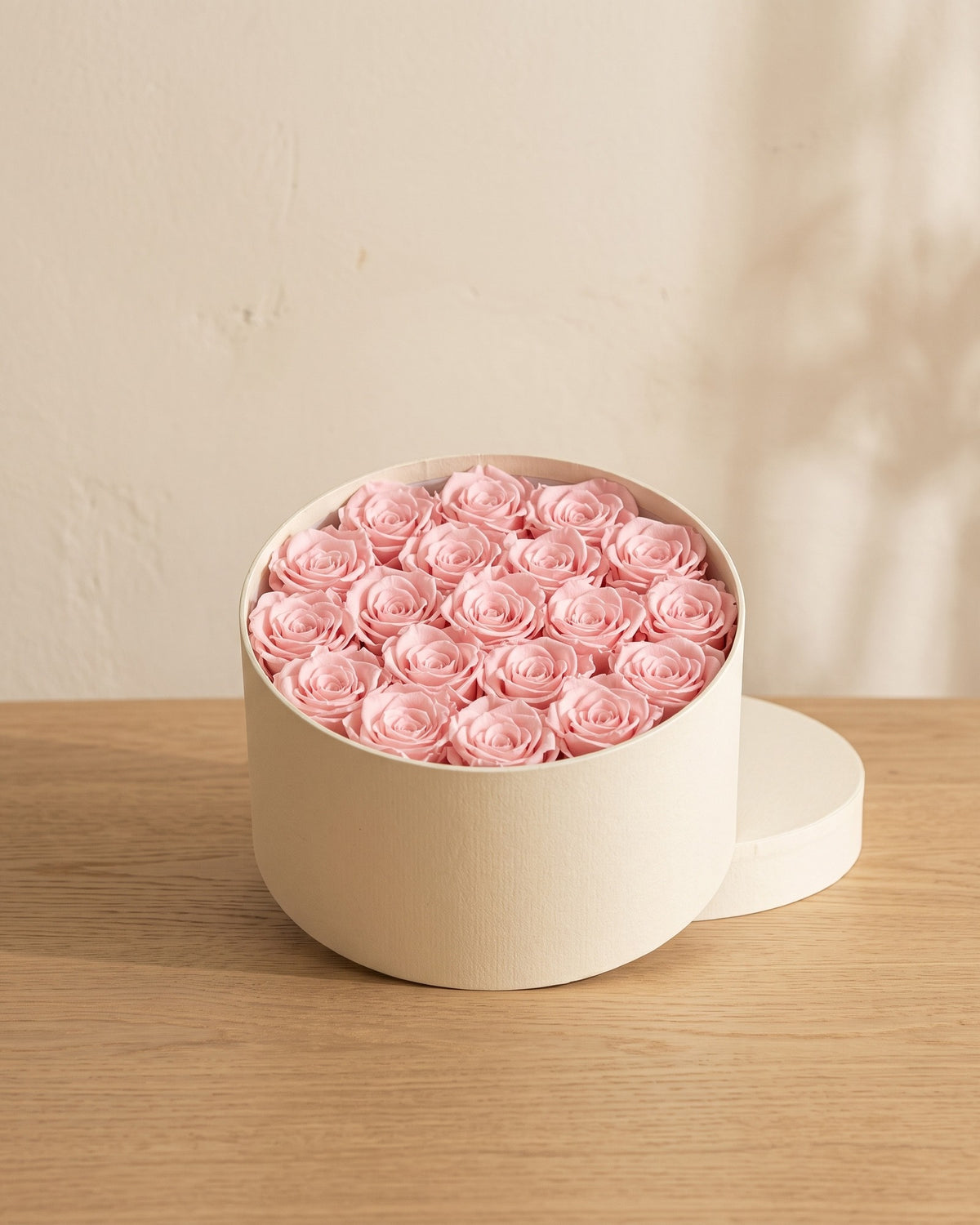 Cabezas de rosa preservada rosa en una caja redonda de regalo, ambientada. Caja de regalo no incluida.