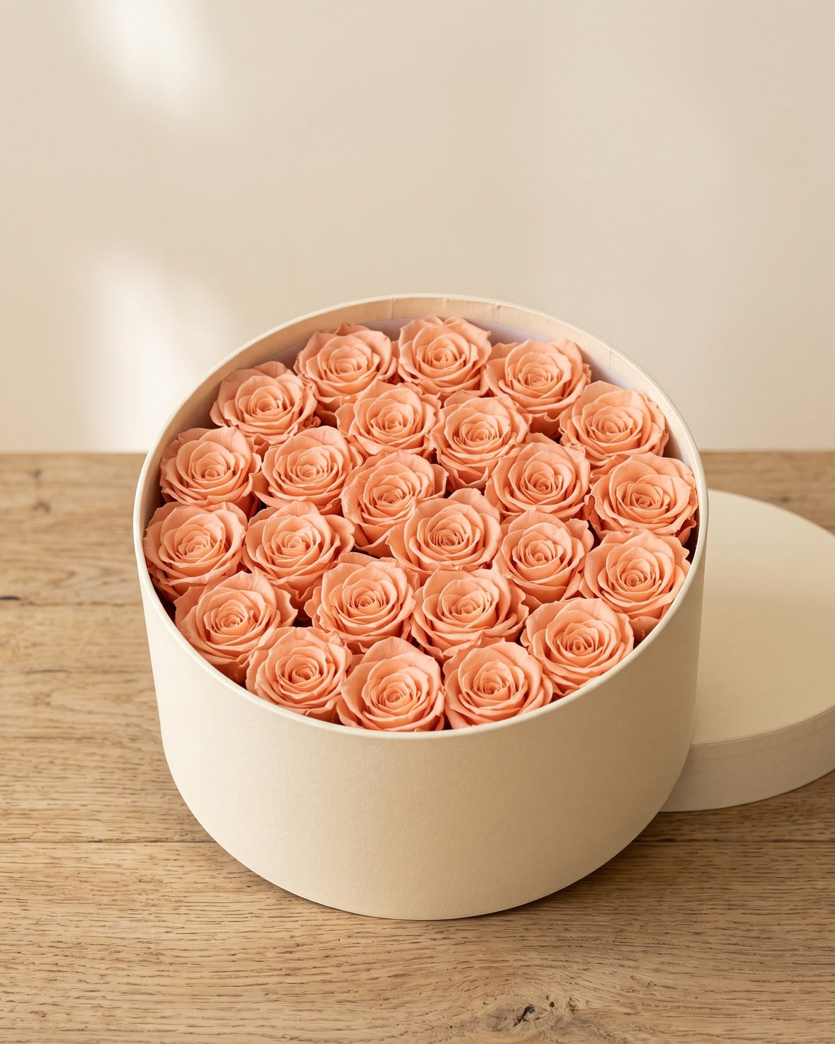 Cabezas de rosa preservada salmón en una caja redonda de regalo, ambientada. Caja de regalo no incluida.