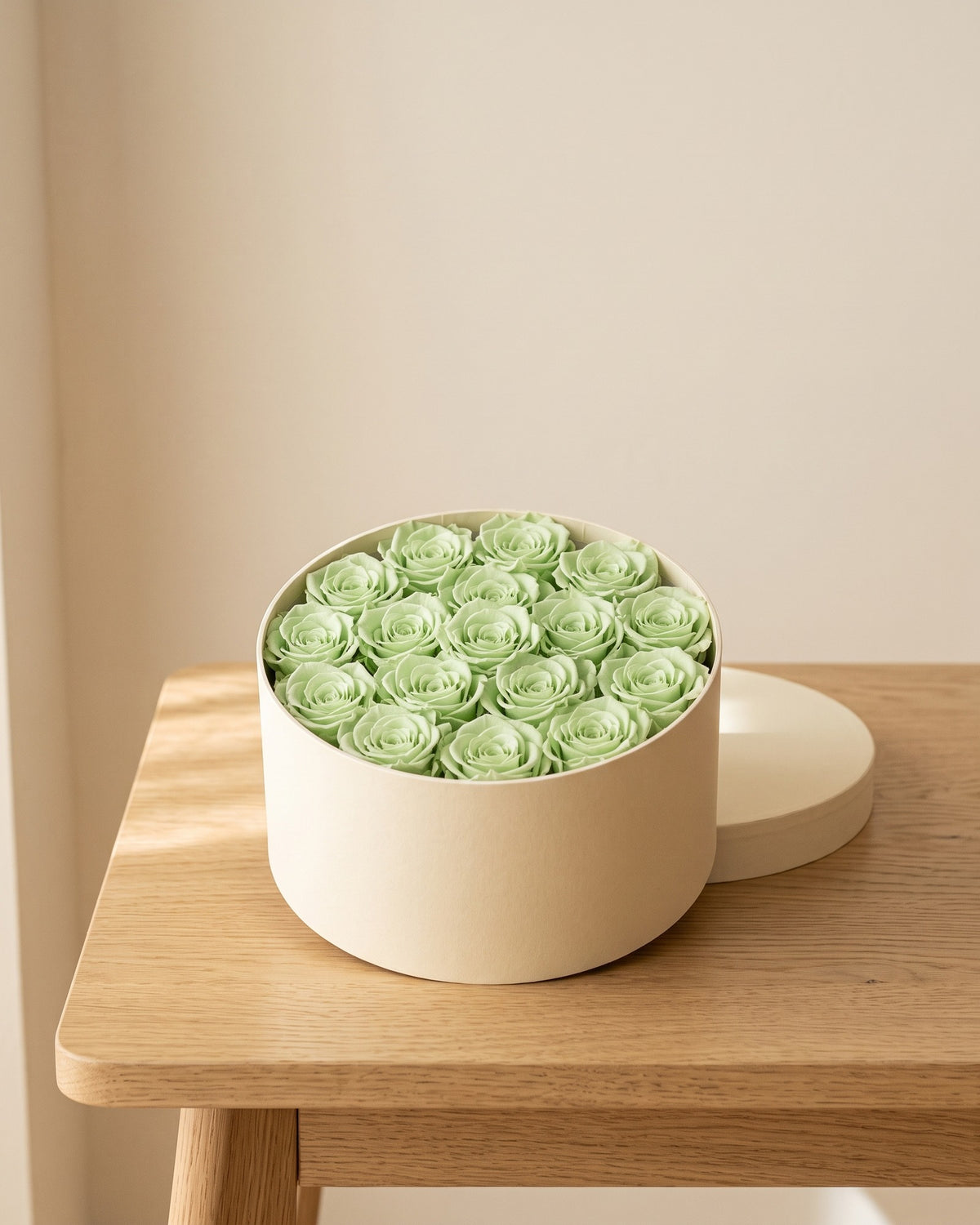Cabezas de rosa preservada verde clara en una caja redonda de regalo, ambientada. Caja de regalo no incluida.