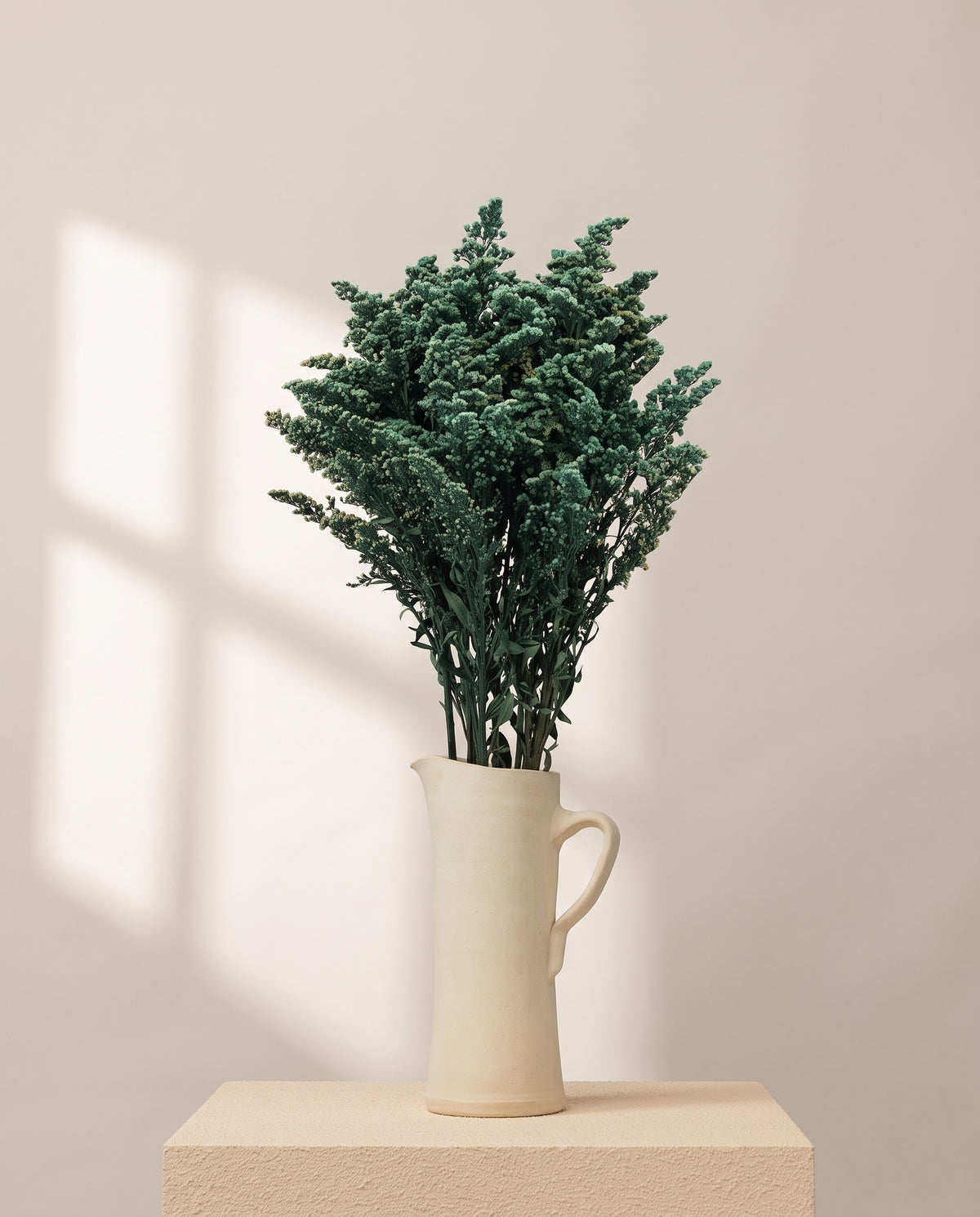 Solidago preservada verde-azulado numa jarra de cerâmica creme. Jarra não incluída.